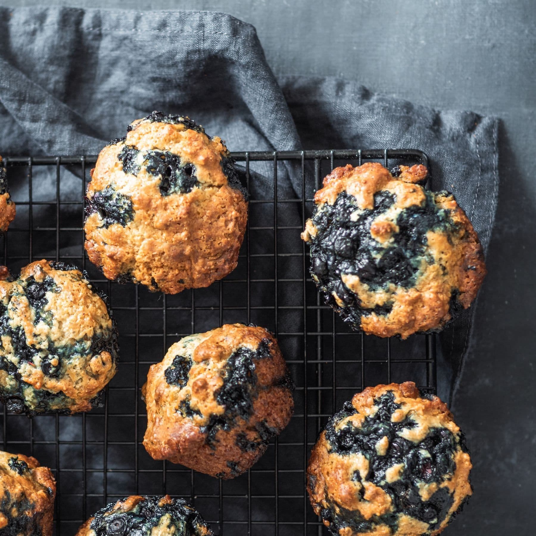 Several blueberry muffins on a cooling rack.